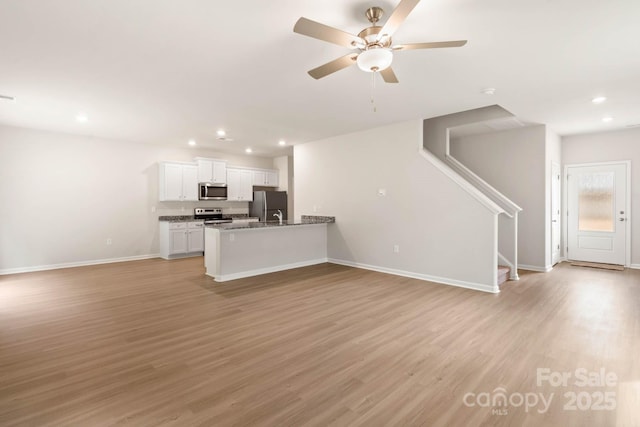 kitchen with light wood finished floors, open floor plan, white cabinetry, and stainless steel appliances