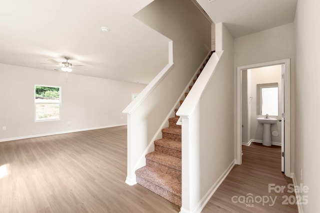 staircase with baseboards, wood finished floors, and a ceiling fan