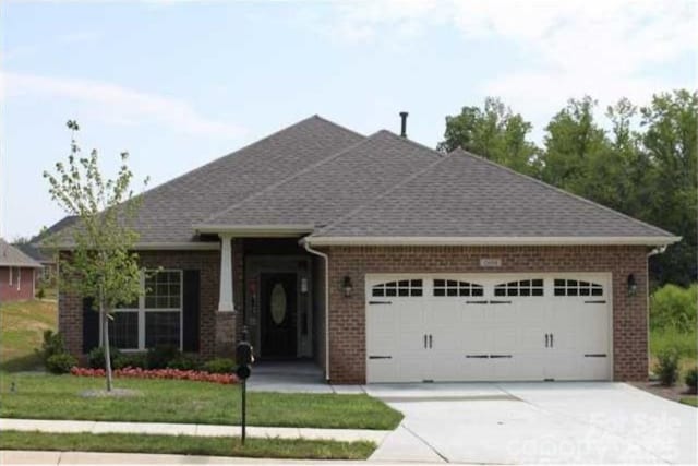 view of front of house featuring concrete driveway, an attached garage, brick siding, and roof with shingles