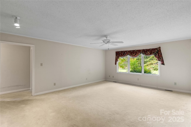 carpeted empty room featuring baseboards, a textured ceiling, ceiling fan, and crown molding