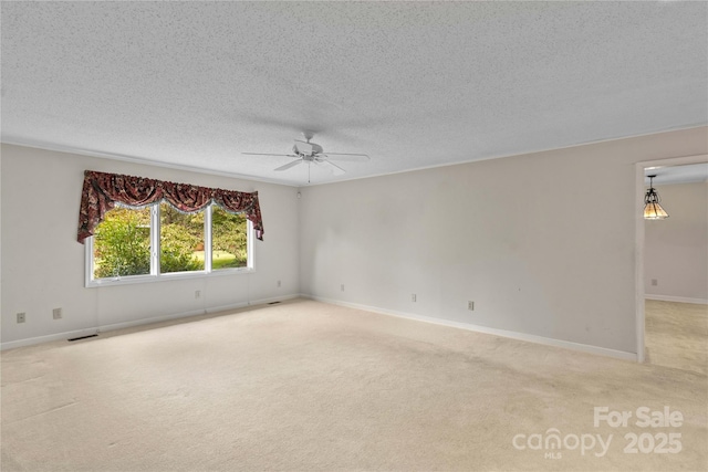 empty room featuring a ceiling fan, baseboards, visible vents, a textured ceiling, and light colored carpet