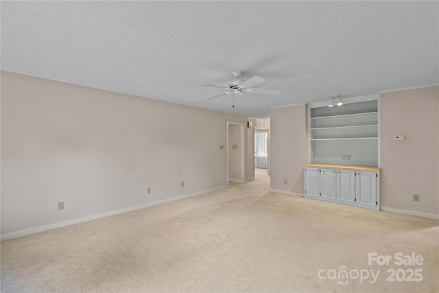 unfurnished room featuring light colored carpet, baseboards, a textured ceiling, and ceiling fan