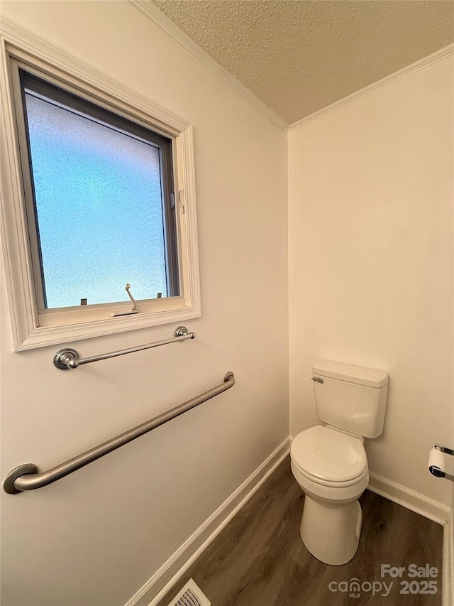 bathroom featuring baseboards, toilet, ornamental molding, wood finished floors, and a textured ceiling