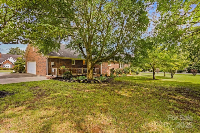 view of front of property featuring brick siding, concrete driveway, a wooden deck, and a front yard