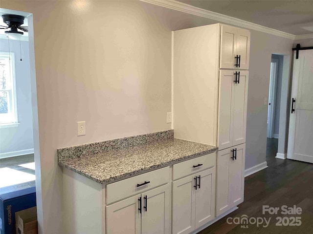 kitchen featuring dark wood finished floors, a barn door, white cabinets, and ornamental molding