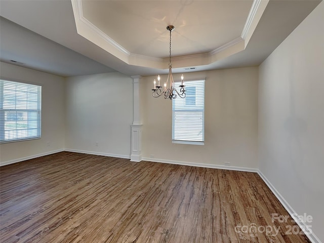 unfurnished dining area with baseboards, dark wood finished floors, decorative columns, crown molding, and a raised ceiling