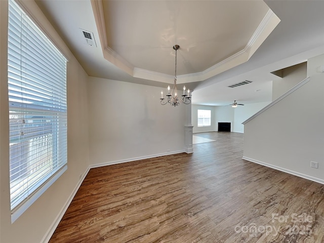 unfurnished dining area with visible vents, a raised ceiling, wood finished floors, and ornamental molding