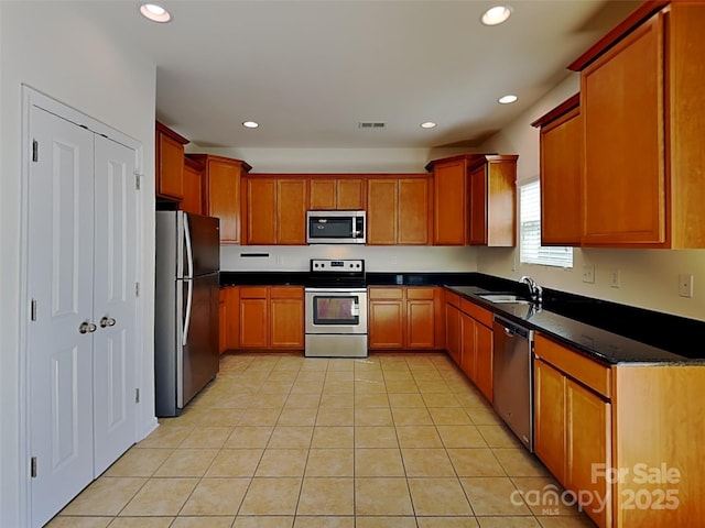 kitchen featuring dark countertops, recessed lighting, light tile patterned flooring, stainless steel appliances, and a sink