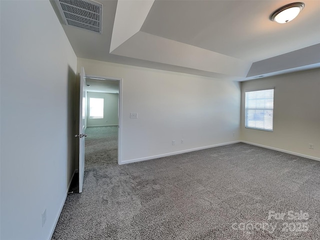 carpeted empty room with visible vents, baseboards, and a tray ceiling