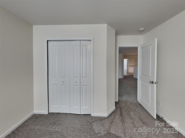 unfurnished bedroom featuring a closet, baseboards, and carpet floors