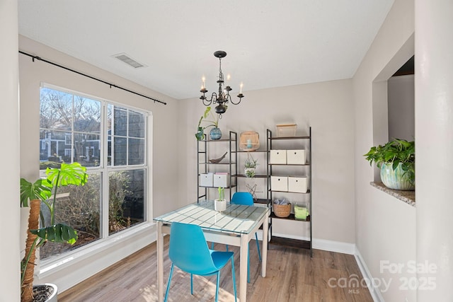 dining space with visible vents, baseboards, wood finished floors, and a chandelier