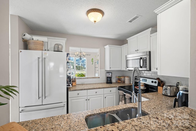 kitchen featuring visible vents, backsplash, appliances with stainless steel finishes, white cabinetry, and a sink