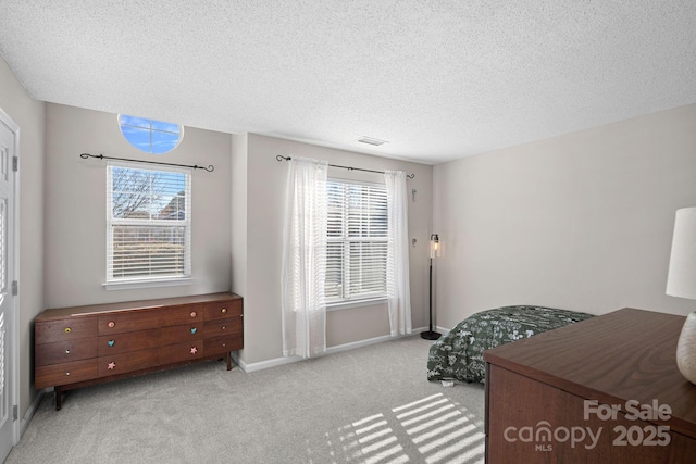 bedroom with visible vents, multiple windows, a textured ceiling, and carpet floors