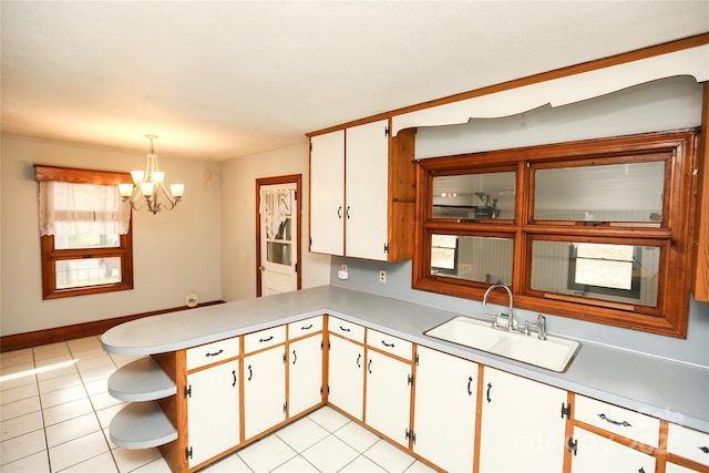 kitchen with light countertops, a chandelier, open shelves, and a sink