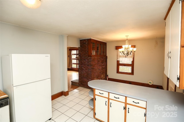 kitchen with white appliances, a peninsula, hanging light fixtures, light countertops, and a notable chandelier