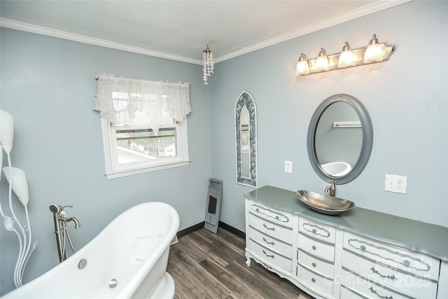 full bath featuring vanity, a freestanding tub, wood finished floors, and ornamental molding