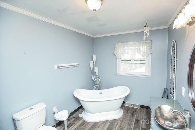 bathroom with visible vents, baseboards, a freestanding bath, toilet, and wood finished floors