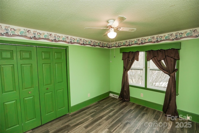 unfurnished bedroom with visible vents, a textured ceiling, baseboards, and wood finished floors