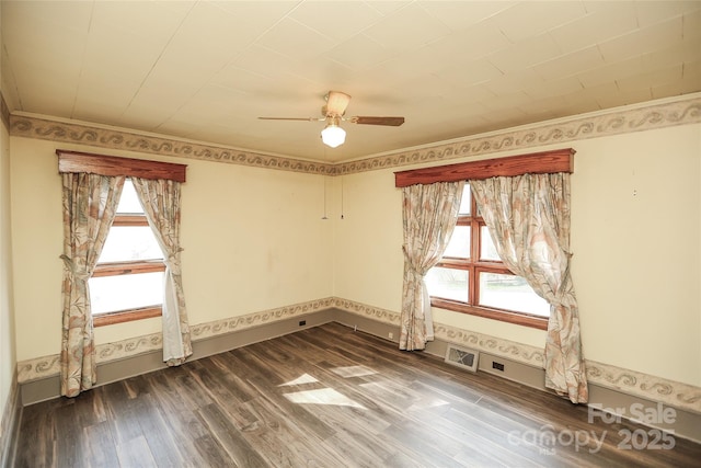 empty room featuring a wealth of natural light, dark wood finished floors, a ceiling fan, and crown molding