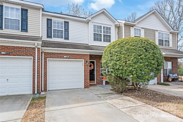 multi unit property with a garage, brick siding, and concrete driveway