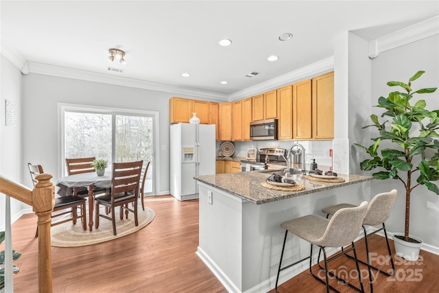 kitchen featuring light wood-style flooring, a sink, stainless steel appliances, a peninsula, and crown molding