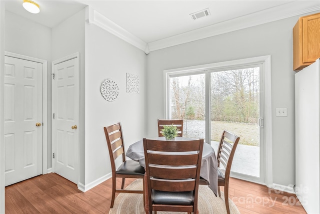 dining area with visible vents, light wood-style flooring, crown molding, and baseboards