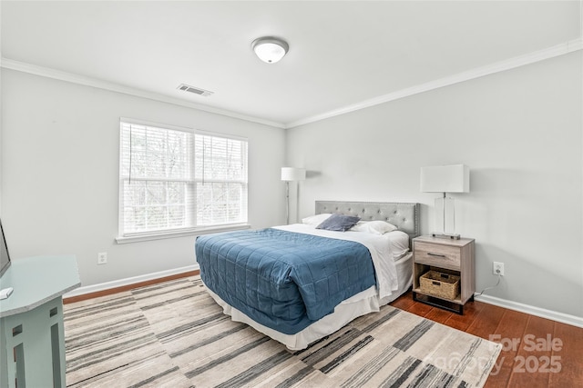 bedroom with visible vents, crown molding, baseboards, and wood finished floors