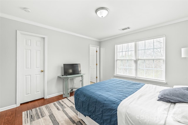 bedroom with visible vents, baseboards, wood finished floors, and ornamental molding