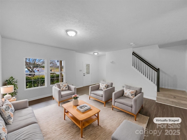 living area with stairway, baseboards, a textured ceiling, and wood finished floors