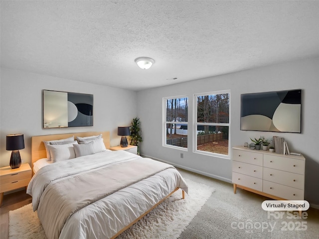 carpeted bedroom featuring visible vents, baseboards, and a textured ceiling