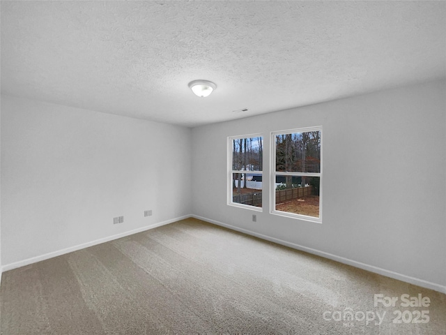 carpeted empty room with baseboards and a textured ceiling