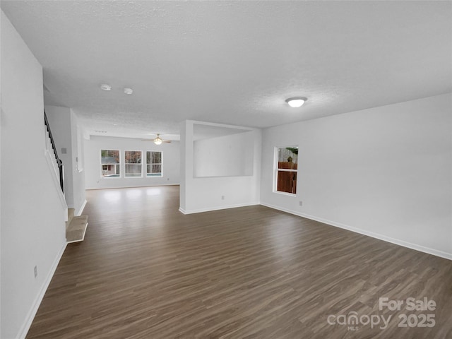 interior space featuring baseboards, dark wood-type flooring, ceiling fan, and a textured ceiling