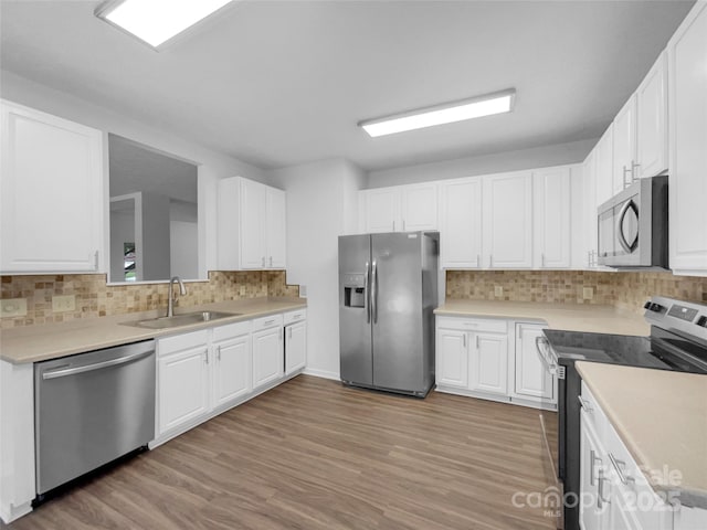 kitchen with a sink, white cabinets, light wood-style flooring, and stainless steel appliances