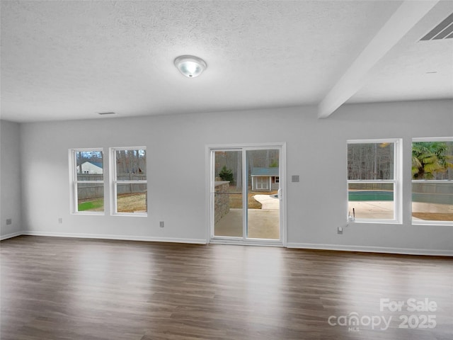 unfurnished room featuring a wealth of natural light, visible vents, a textured ceiling, and dark wood finished floors