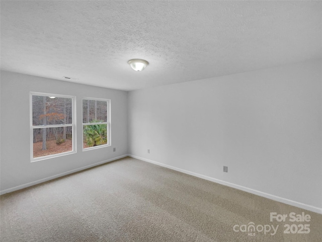 empty room featuring carpet flooring, visible vents, a textured ceiling, and baseboards