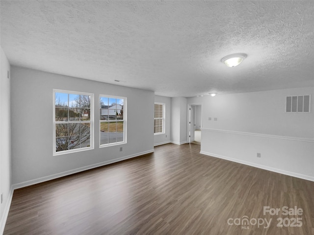 unfurnished living room featuring visible vents, a textured ceiling, dark wood-type flooring, and baseboards