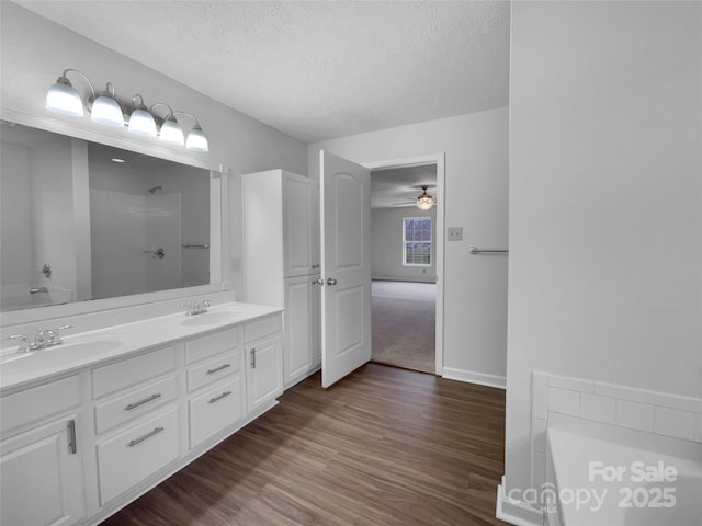 full bath featuring a sink, a textured ceiling, walk in shower, and wood finished floors