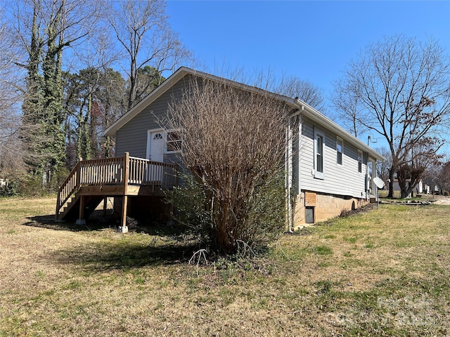 view of side of home with a yard, a deck, and stairway