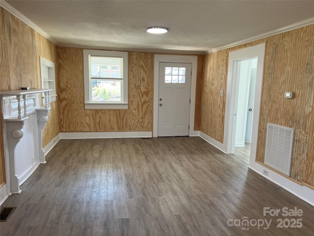 foyer featuring visible vents, dark wood-style flooring, a textured ceiling, and ornamental molding