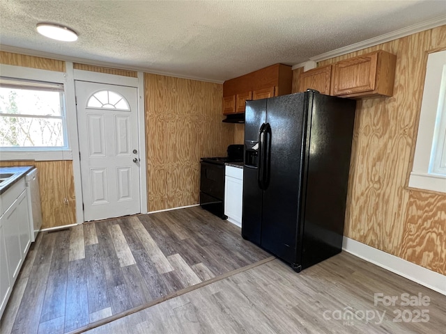 kitchen with black appliances, crown molding, under cabinet range hood, wood finished floors, and a textured ceiling