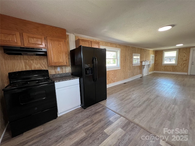 kitchen with a wealth of natural light, black appliances, under cabinet range hood, a textured ceiling, and wood finished floors