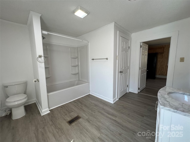 bathroom featuring toilet, wood finished floors, visible vents, and a textured ceiling