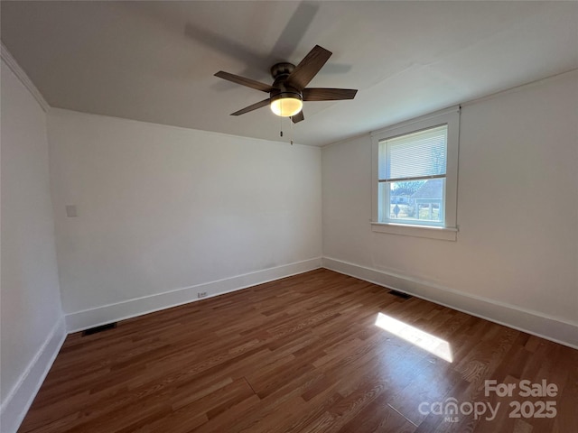 unfurnished room with visible vents, wood finished floors, baseboards, and ceiling fan