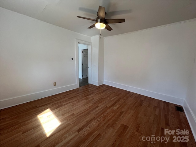 spare room featuring dark wood finished floors, a ceiling fan, and baseboards