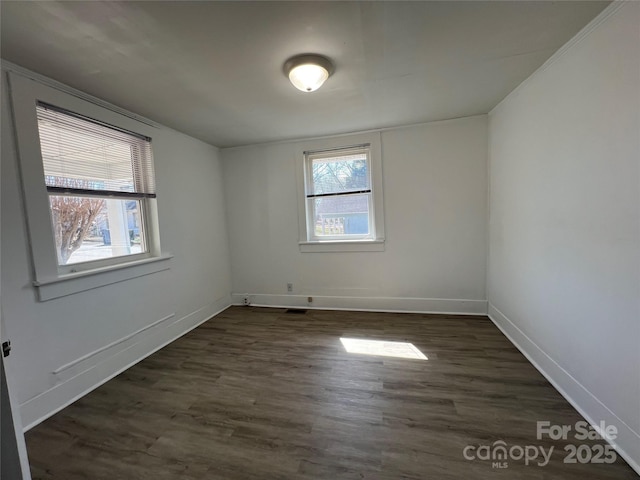 unfurnished room featuring dark wood-type flooring, baseboards, and a wealth of natural light