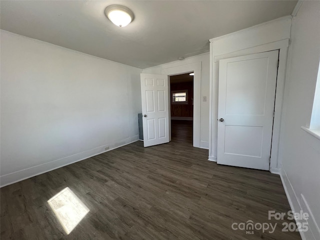 unfurnished bedroom with dark wood-type flooring and baseboards