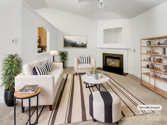 carpeted living room featuring a glass covered fireplace, vaulted ceiling, a ceiling fan, and baseboards