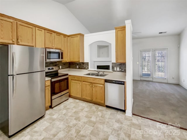 kitchen featuring lofted ceiling, a sink, decorative backsplash, light countertops, and stainless steel appliances