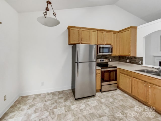 kitchen with tasteful backsplash, light countertops, vaulted ceiling, appliances with stainless steel finishes, and a sink