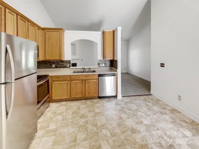 kitchen with a sink, light countertops, vaulted ceiling, appliances with stainless steel finishes, and tasteful backsplash